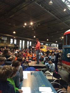 Ton Mackaaij spreekt de menigte kinderen toe tijdens het toernooi van 2016 in het Spoorwegmuseum.